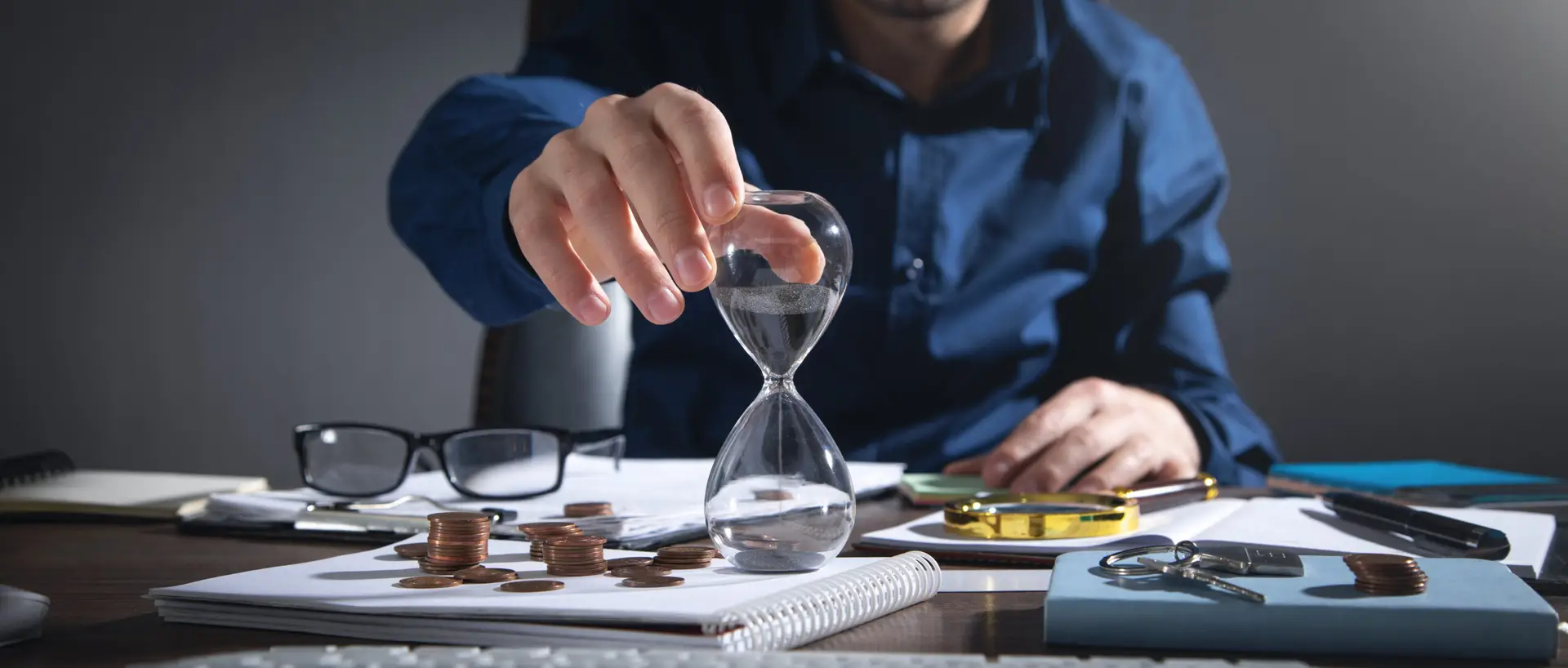 businessman holding hourglass coins business objects desk scaled